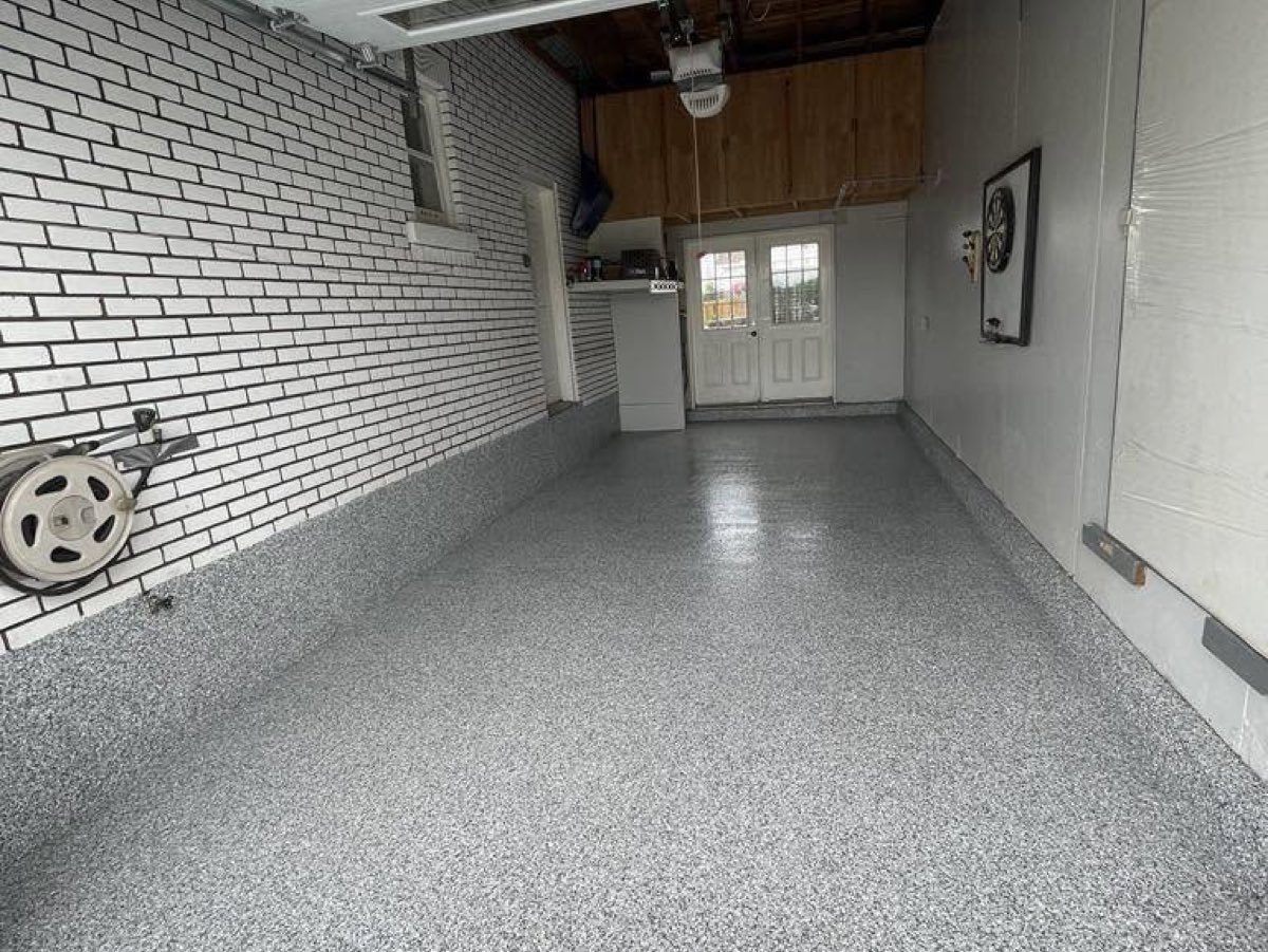 Garage après travaux, plancher époxy gris à flocons et mur de brique repeint en blanc