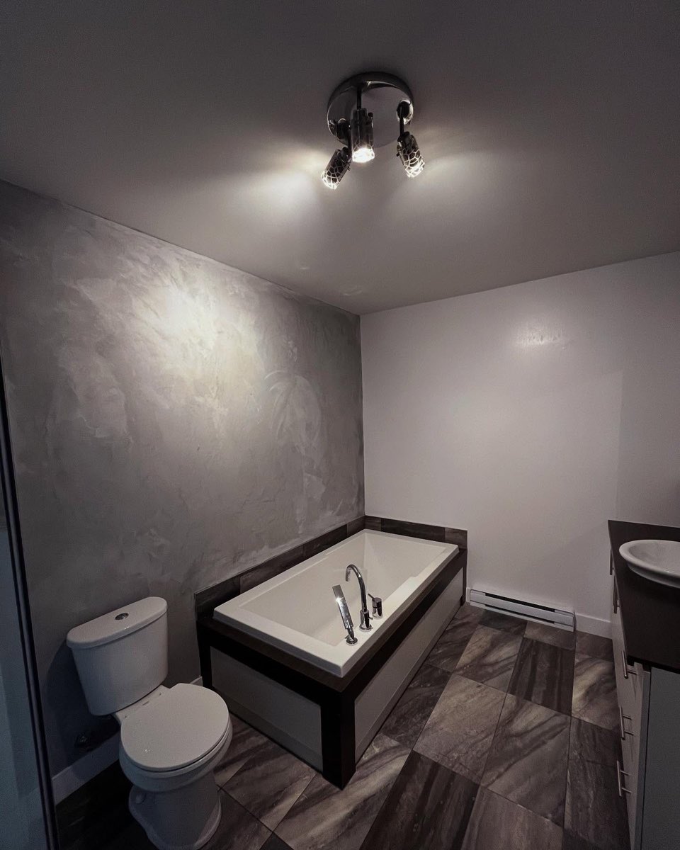 Salle de bain avec mur en enduit décoratif gris nuage autour d'un bain encastré