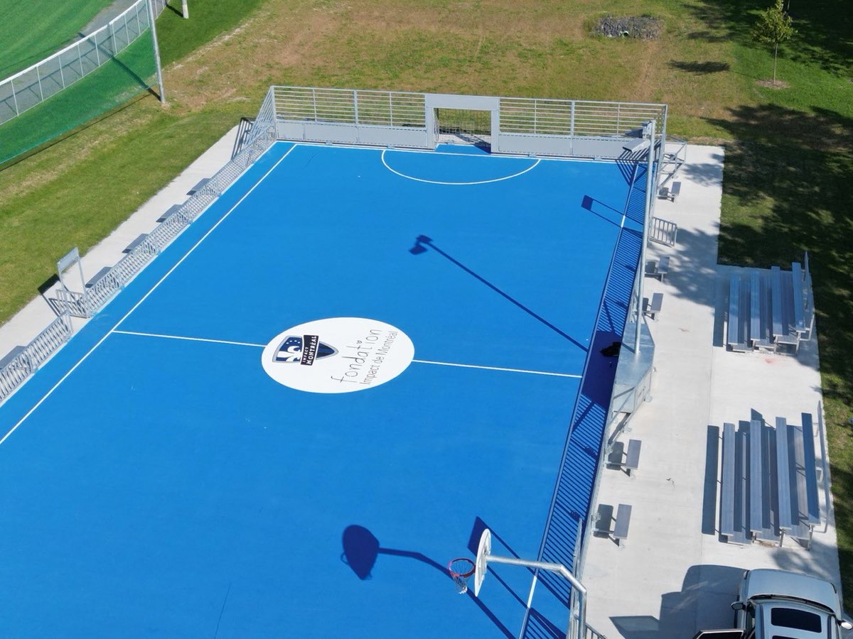 Terrain de basketball à surface acrylique bleue vu de haut, bandes, estrades et logo central